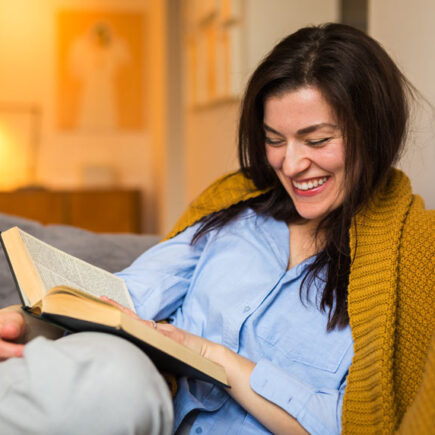 Kvinde læser litteratur i sofa