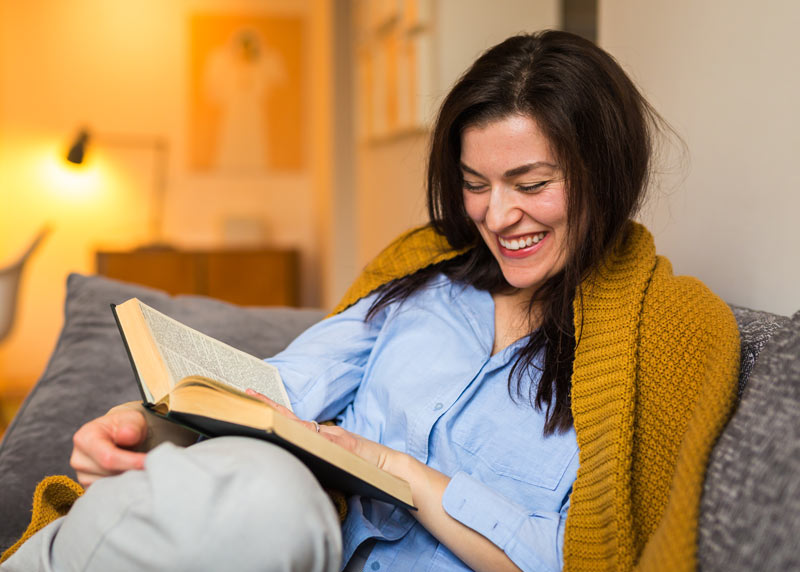 Kvinde læser litteratur i sofa